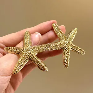 Dettaglio degli orecchini a lobo a forma di stella marina dorata per look da vacanza