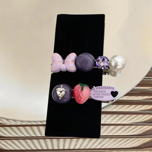 Close-up detail of elegant purple duckbill hair clips with strawberry pearl and bow motifs