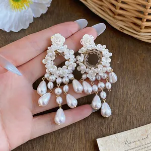 Dettaglio ravvicinato di eleganti orecchini a fiore e nappa di perle in stile francese