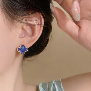 Detailed close-up showing elegant blue camellia flower stud earrings with gold trim