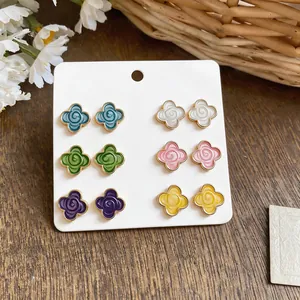 Detailed view of colorful camellia flower stud earrings set with gold-tone edges.