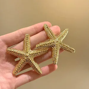 Primo piano dettagliato di eleganti orecchini a stella marina dorati con finitura metallica