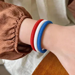 Vue rapprochée de joncs à texture ressort rouge, blanc et bleu sur le poignet d'une femme