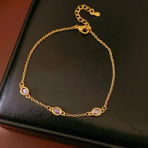 Eleganter Goldketten-Armband mit drei ovalen lila Edelsteinen auf schwarzem Hintergrund