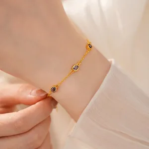 Elegantes goldfarbenes Kettenarmband mit lila ovalen Edelsteinen am Handgelenk