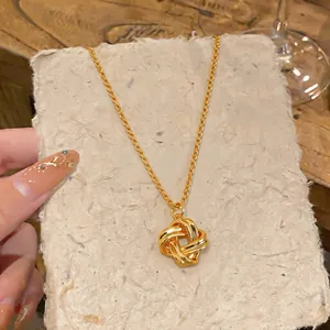 Gros plan d'un collier pendentif nœud doré sur du papier texturé rustique