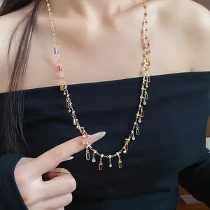 Detailed view of a dainty gold necklace with colorful rectangle charms worn by a model.