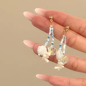Close-up detail of Bohemian style blue beaded earrings with white shell and crystal charms
