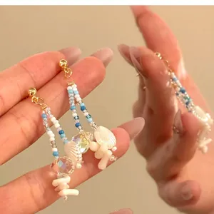 Detail view of Bohemian shell drop earrings with blue and white beads