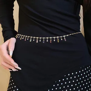 Detailed view of gold waist chain featuring colorful square pendants on black outfit