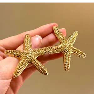 Dettaglio di grandi orecchini a forma di stella marina dorata con superficie testurizzata