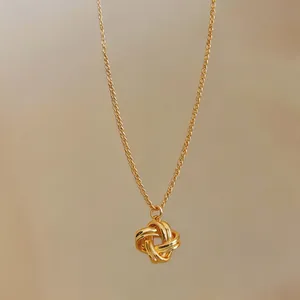 Gros plan d'un pendentif nœud doré vintage français sur un collier à chaîne fine.