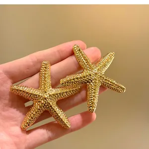 Primo piano di orecchini a stella marina dorati con texture per uno stile da vacanza.