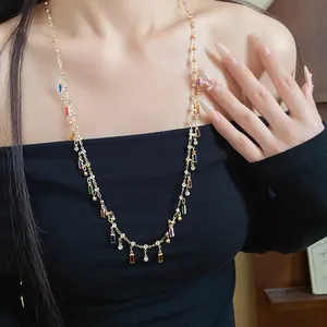 Detail of gold necklace featuring colorful square acrylic pendants and crystals on a model