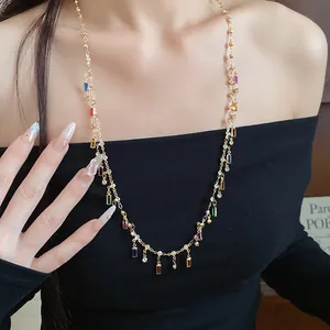Close-up of gold necklace with colorful square acrylic pendants and sparkling rhinestones
