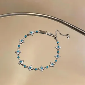 Dettaglio bracciale a fiori in argento con pietre di zirconia blu e bianche.