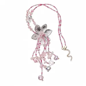 Elegante collana di perline rosa con ciondolo floreale e lunghe nappe boho.