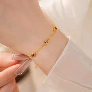 Nahaufnahme eines filigranen Goldarmbands mit eleganten lila ovalen Edelsteinen am Handgelenk