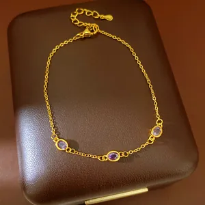 Detailansicht eines eleganten Goldarmbands mit drei violetten ovalen Edelsteinen.