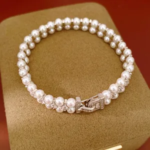 Close-up detail of elegant double-row white pearl bracelet with sparkling crystal clasp