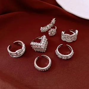 Set of elegant silver-toned rhinestone rings displayed on luxury red velvet fabric.