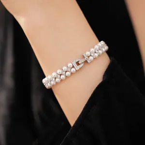 Detailed view of elegant double-layered pearl bracelet with zirconia D-clasp on wrist