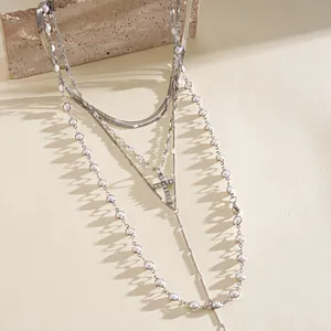 Dettaglio del set di 5 collane argentate a strati con perle e pendente a croce con diamanti.