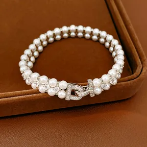 Macro detail of elegant double-layer pearl bracelet with sparkling crystal D-clasp.