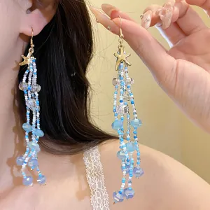 Detail shot of blue and white beaded starfish drop earrings for seaside holiday style