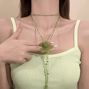 Primo piano di una collana in perle di vetro verde fatta a mano con ciondolo fiore.