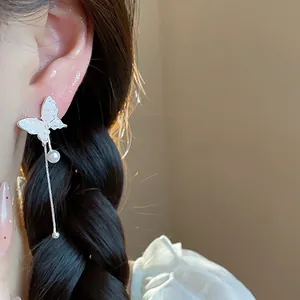 Elegant silver butterfly tassel earrings with faux pearl detail shown on a model
