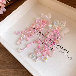 Squisito primo piano di orecchini a nappa con perline di fiori rosa su tessuto crema.