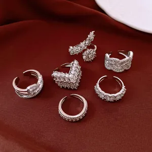 Detailed view of multiple silver rhinestone rings with floral designs on luxury red silk background