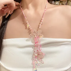 Primo piano di una collana di perline rosa con ciondolo a fiore e lunghe nappe sul collo