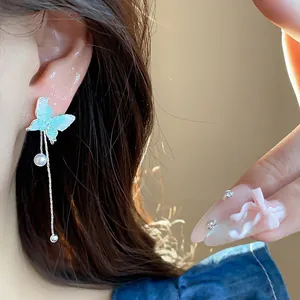 Close-up detail of a blue glass butterfly tassel earring with pearl drop