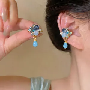Macro detail of vintage French style blue water drop ear clips shown on the model's ear