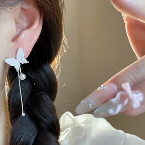 Silver butterfly tassel earrings with pearl detail shown on a model