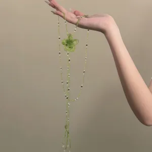Dettaglio di una collana in perline di vetro verdi con fiore fatto a mano e nappe eleganti
