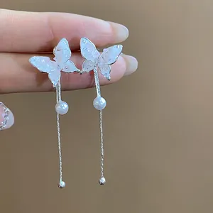 Detail showing elegant glass butterfly earrings with small pearls and silver tassels