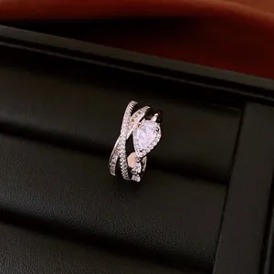 Close-up of elegant criss-cross silver ring with pear-shaped center stone and pavé accents