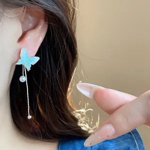Close-up of elegant butterfly tassel pearl earrings with silver needle worn on model ear