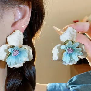 Primo piano degli orecchini a fiore in smalto e tessuto con petali azzurri e centro viola