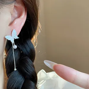 Close-up view of elegant silver butterfly tassel earrings featuring a delicate pearl.