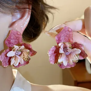 Primo piano di orecchini a fiore rosa con petali in tessuto e finitura smalto.