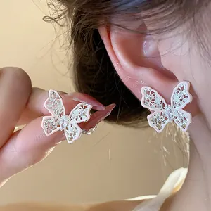 Dettaglio di eleganti orecchini a farfalla rosa traforati con pietre di zircone brillanti