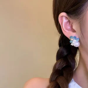 Elegant detail of a blue bead and white pearl earring featuring zircon accents