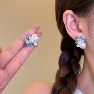 Detailed view of elegant blue crystal and pearl stud earrings worn by model