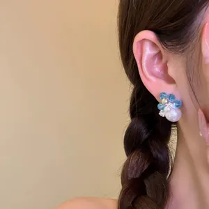 Elegant close-up view of a floral beaded pearl earring worn on an Asian model's ear.