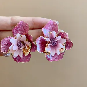 Dettaglio orecchini floreali in smalto rosa con eleganti centri in morbido tessuto.