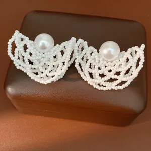 Primo piano di orecchini a perla bianca traforati con elegante perla centrale